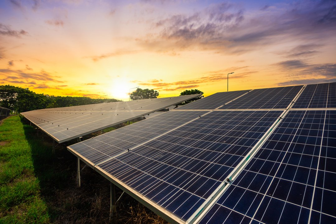 Painéis solares captando luz do sol ao entardecer, representando o uso de energia híbrida e sustentável.
