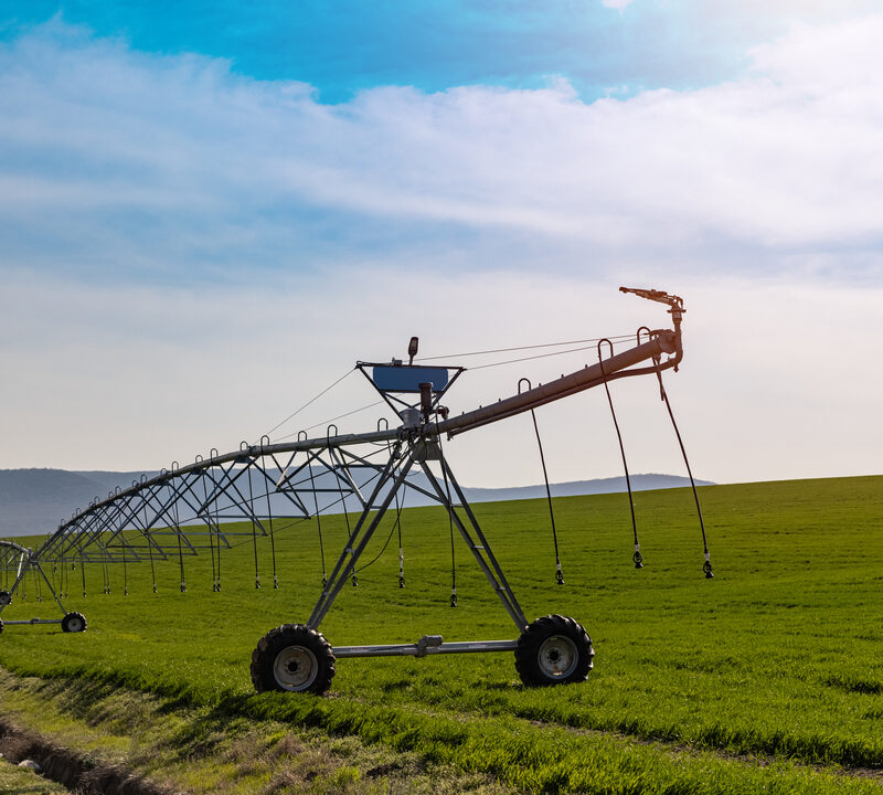 Sistema de pivô de irrigação em funcionamento em lavoura, distribuindo água de forma uniforme no campo para aumentar a produtividade agrícola.