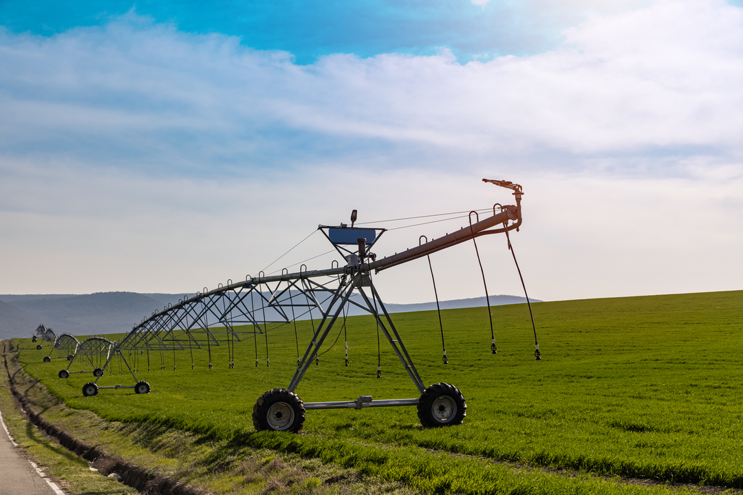 Sistema de pivô de irrigação em funcionamento em lavoura, distribuindo água de forma uniforme no campo para aumentar a produtividade agrícola.