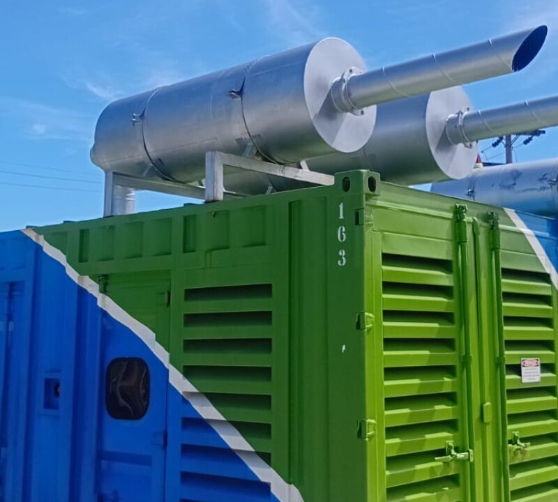 Contêineres industriais coloridos com sistemas de exaustão metálicos instalados no topo, utilizados para geração ou controle de energia.