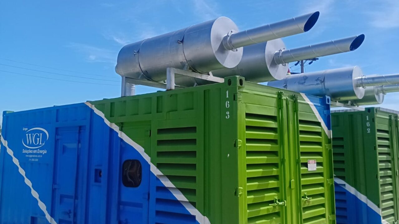 Contêineres industriais coloridos com sistemas de exaustão metálicos instalados no topo, utilizados para geração ou controle de energia.