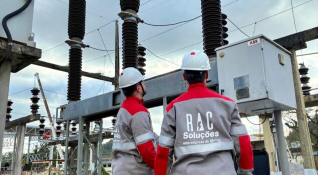 Profissionais do setor elétrico realizam inspeção em subestação de energia utilizando equipamentos de proteção individual.