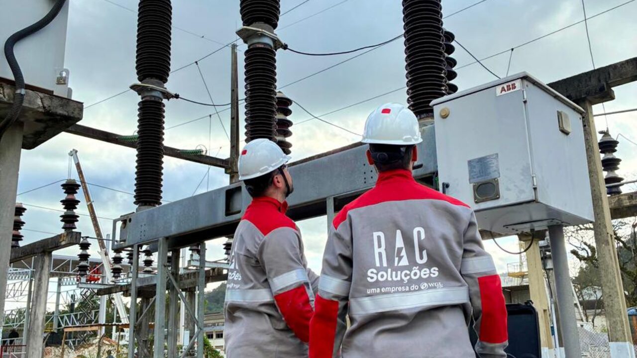 Profissionais do setor elétrico realizam inspeção em subestação de energia utilizando equipamentos de proteção individual.